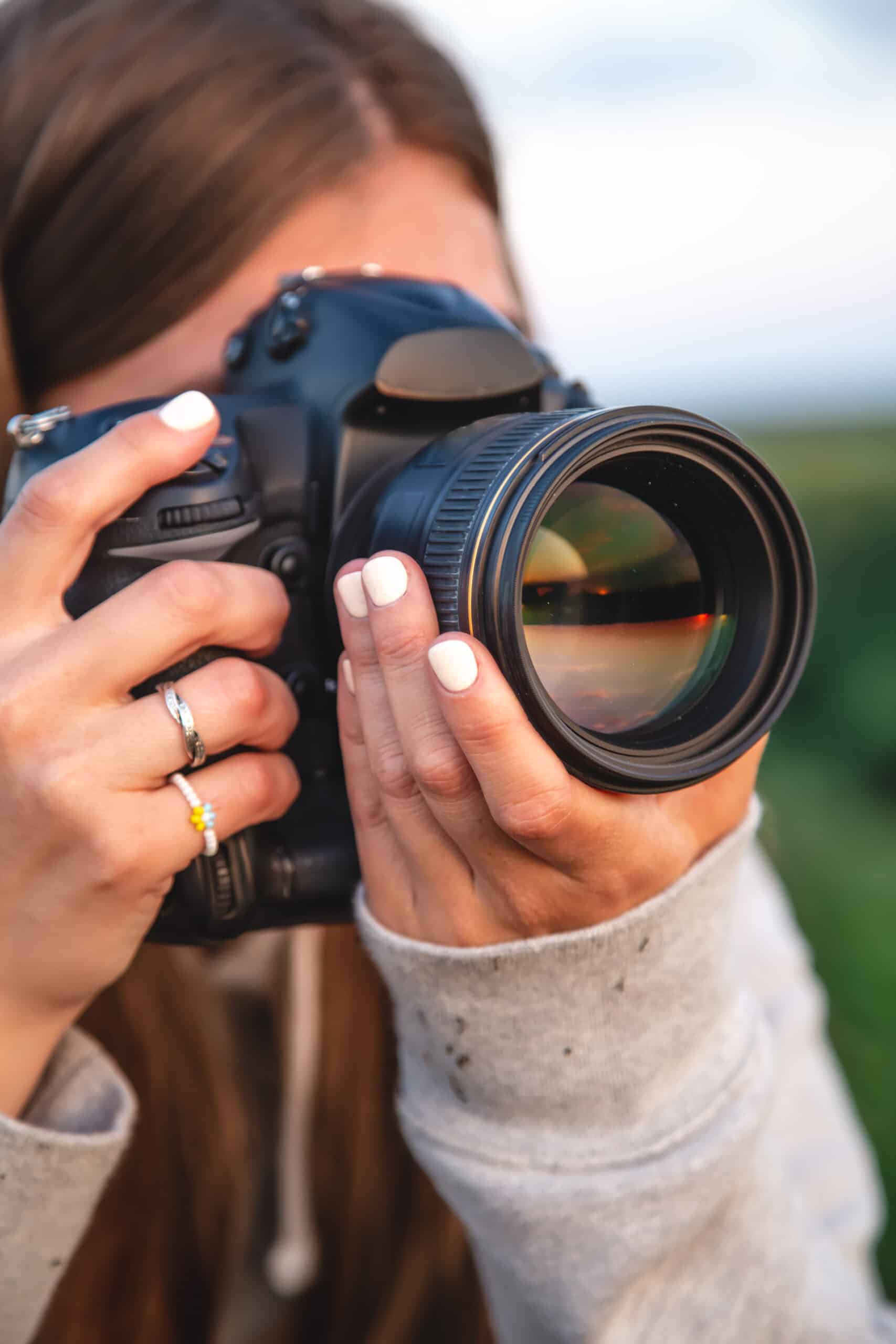 A young woman with a professional camera takes a photo in nature.